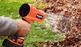 a person using a leaf blower on leaves in a yard
