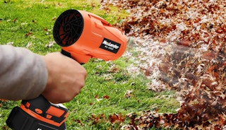 a person using a leaf blower on leaves in a yard