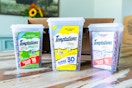 three tubs of cat treats on a hardwood floor