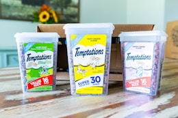 three tubs of cat treats on a hardwood floor