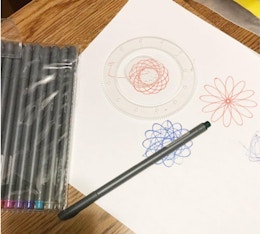 a pack of pen on top of a drawing on a table