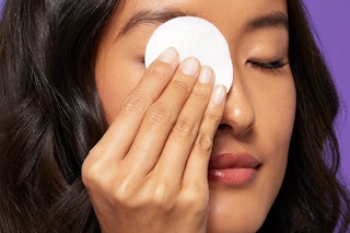 A woman removing her makeup with a cotton pad