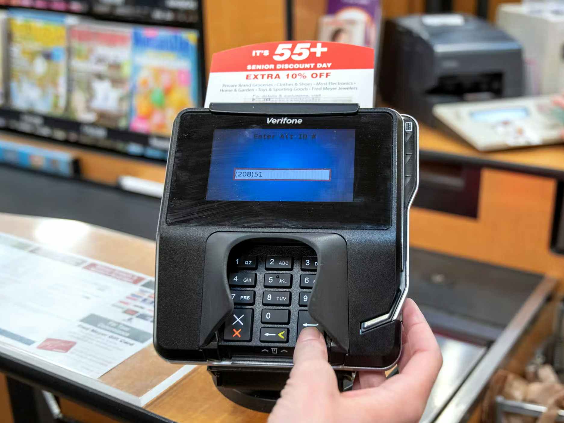 person entering phone number at card reader in kroger checkout