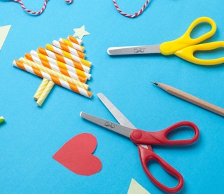 two small scissors and a craft project on a baby blue surface