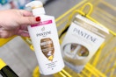 hand holding a bottle of pantene shampoo above a yellow shopping cart