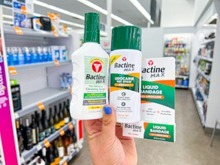 Someone holding up some Bactine Max products in a Walgreens