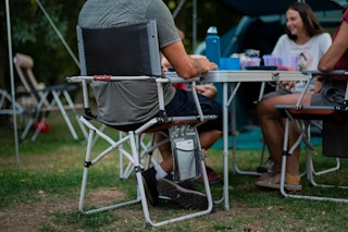 Someone sitting in a Decathlon camping chair around a camping table with friends