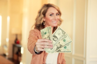 Heather with money in her hand and smiling at the camera.