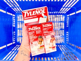 hand holding 3 tylenol products over a walmart basket