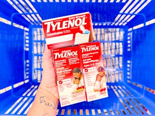 hand holding 3 tylenol products over a walmart basket