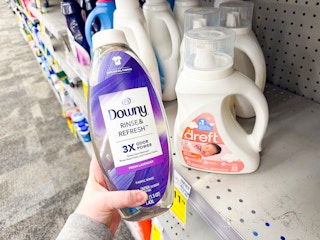 person holding a bottle of downy rinse & refresh by dreft detergent
