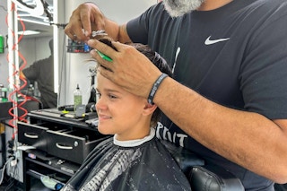 A barber cutting a young boy's hair
