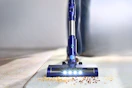 Lifestyle image of a blue PrettyCare Cordless Vacuum Cleaner (close up shot of crumbs on a carpet)