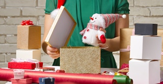 A person wrapping a little snowman for a holiday gift