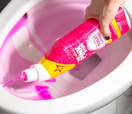 a hand pouring a bottle of toilet bowl cleaner in the toilet 