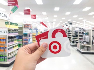 hand holding Target RedCard debit card and gift card inside Target store