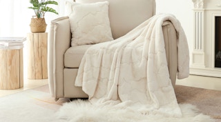 a velvet faux fur cream colored blanket draped over a chair