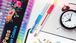 colorful gel pens on a table with a clock