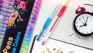 colorful gel pens on a table with a clock