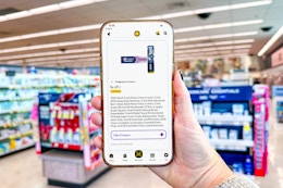 hand holding a smartphone displaying a kcl 1-clip crest coupon