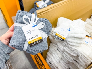 hand holding a gray set of wash cloths next to a white set