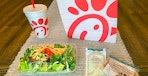 a chick fil a side salad sitting next to a chick fil a bag and drink