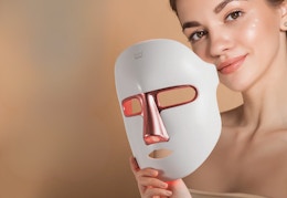 person holding a white LED light face mask