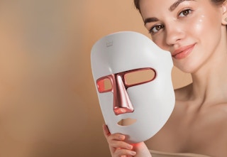 person holding a white LED light face mask