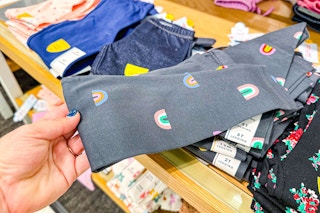 hand grabbing a pair of toddler leggings off a target shelf