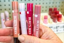 person holding 4 tubes of burt's bees shimmer lip gloss