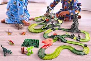 Lifestyle image of the USA Toyz Dinosaur Dash Track being played with by children sitting on the floor