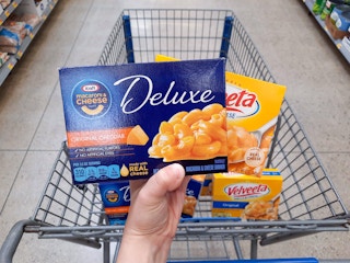 Kraft Deluxe Mac and Cheese and Velveeta Shells and Cheese held over Walmart shopping cart