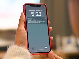 person holding phone with bath and body works candle day notification