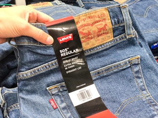 A person's hand picking up some Levi's jeans.