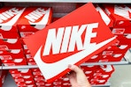 A person's hand taking a box of Nike shoes from a shelf.