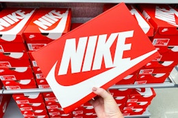 A person's hand taking a box of Nike shoes from a shelf.