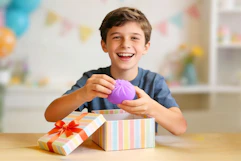 Boy holding a purple squishy dumpling toy in his hand 