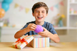 Boy holding a purple squishy dumpling toy in his hand 