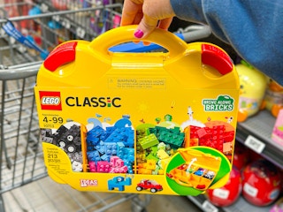 hand holding lego-suitcase in front of walmart cart