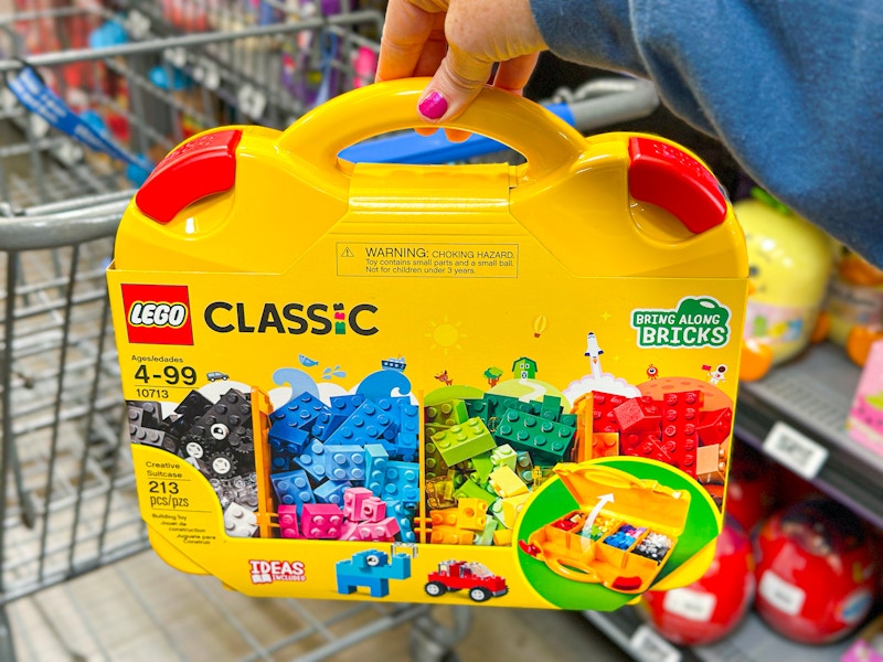 hand holding lego-suitcase in front of walmart cart
