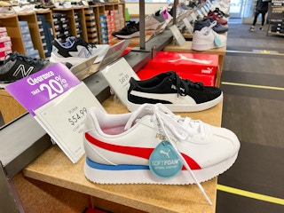 A row of shoes for sale with a purple sign next to one of them that says "Clearance, 20% off"