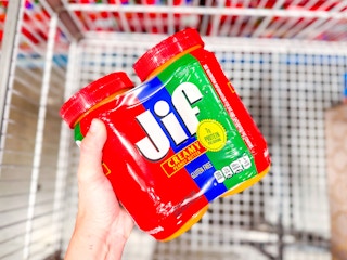 hand holding two pack of peanut butter over a cart