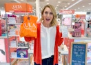 A woman in Ulta holding a bag and receipt up, looking excited.