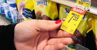 a person holding up a grocery sale tag in a store