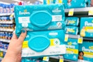 hand holding two packs of pampers baby wipes in a store aisle
