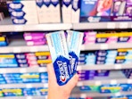 2 Crest 3D White Toothpaste Tubes held up in front of oral hygiene aisle in Walmart 