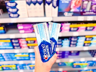 2 Crest 3D White Toothpaste Tubes held up in front of oral hygiene aisle in Walmart 