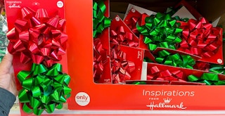 A person holding a two pack of bows next to a box full of them for sale in a store.