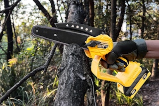 yellow cordless mini chainsaw being used on branch
