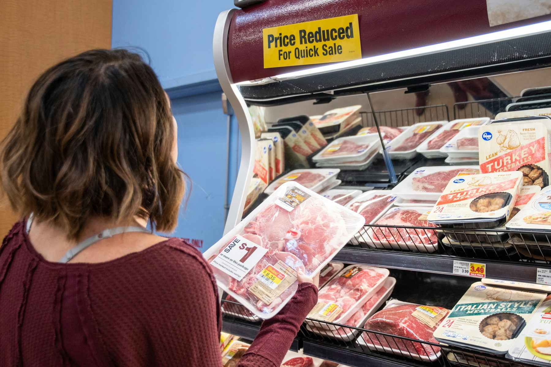 A person looking at a clearance section in a store's meat department.